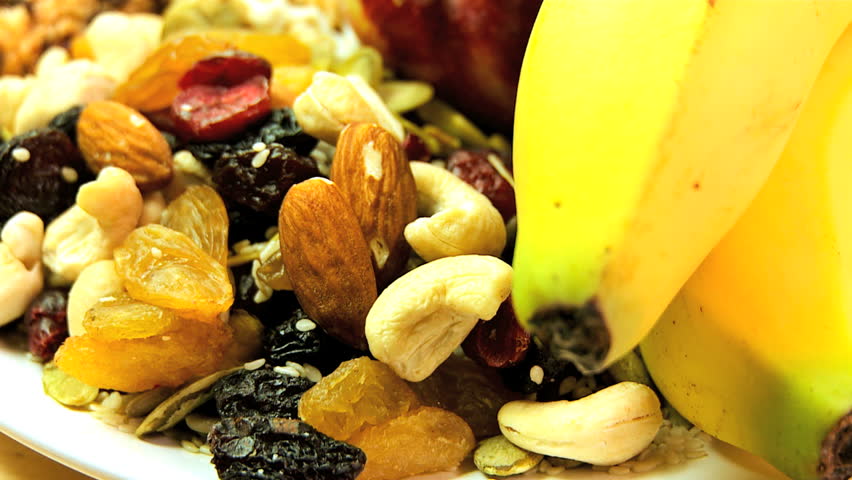 Selection of fresh & dried fruits, nuts & cereal bars to eat as healthy snack food options