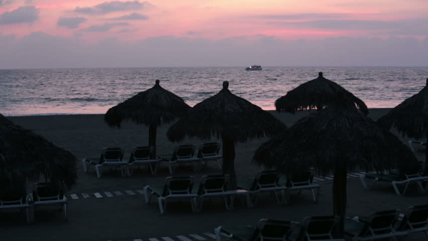 Tropical sunset cruise cabana umbrella ocean beach. Nuevo Vallarta, near Puerto Vallarta, Mexico luxury resort hotel complex. Beach tropical palm umbrellas, lounge chairs sunbathing and recreation. 