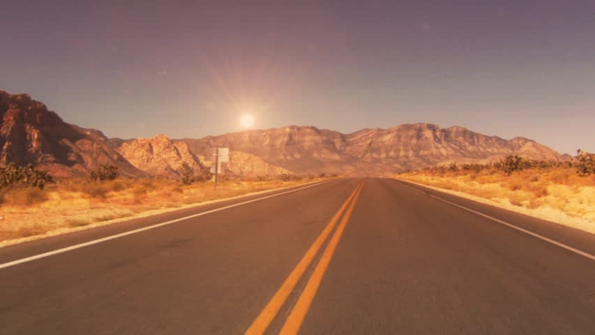 Desert road with sun and mountains