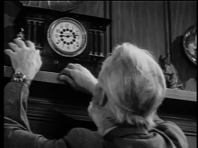 Rear view of man trying to wind antique clock