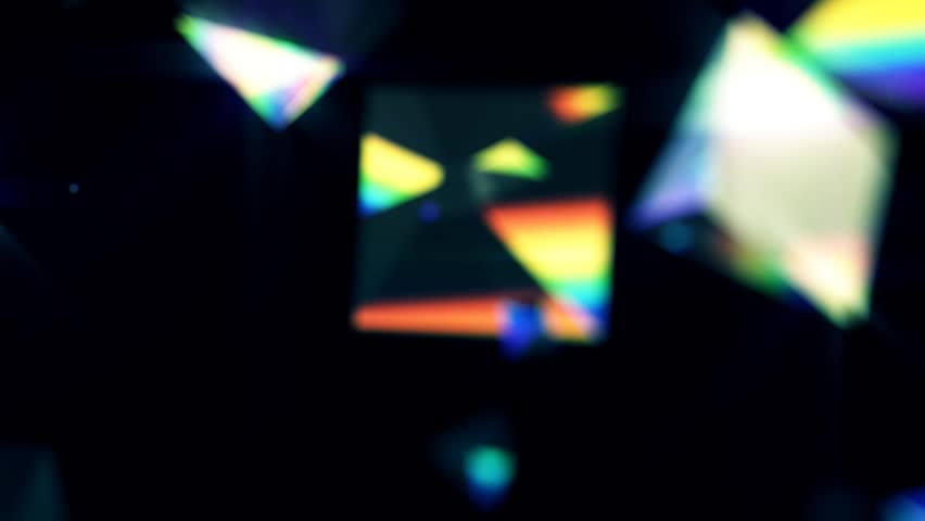 Rainbow triangle prisms float across blurred on black background