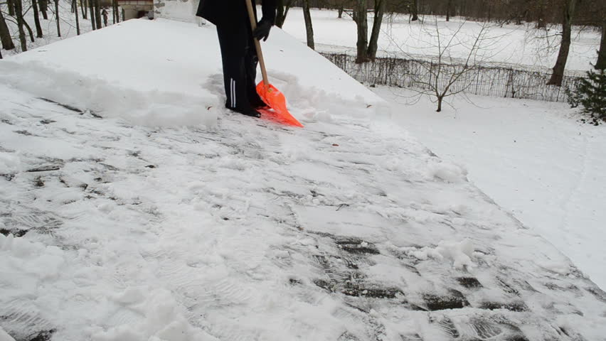 man with plastic orange shovel tool push clean snow from roof. winter works.