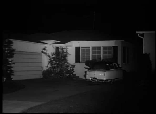 1950s car pulling out of suburban driveway at night