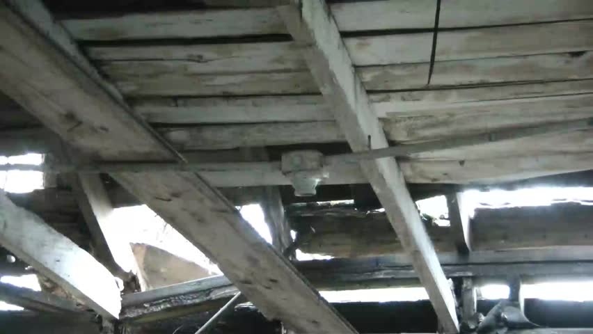 Ironic clip of man screwing light bulb in at old barn that has been abandoned for many years, and is in rough condition.