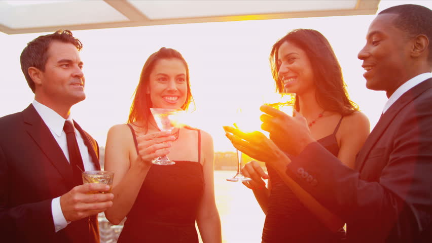 Young multi ethnic pretty girls drinking with attractive men at sunset outdoor party with lens flare. shot on RED EPIC.