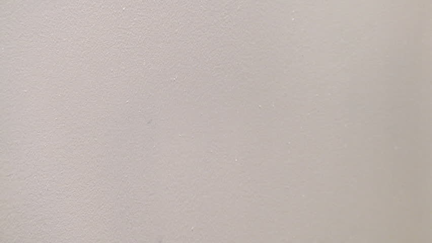 painter rolls red paint onto a white wall