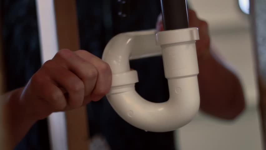 Plumber working on sink pipes