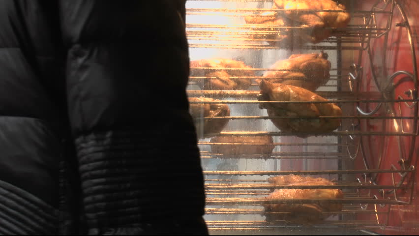 Customer waits for vendor by outdoor chicken roaster to buy hot, cooked takeout. 1080p