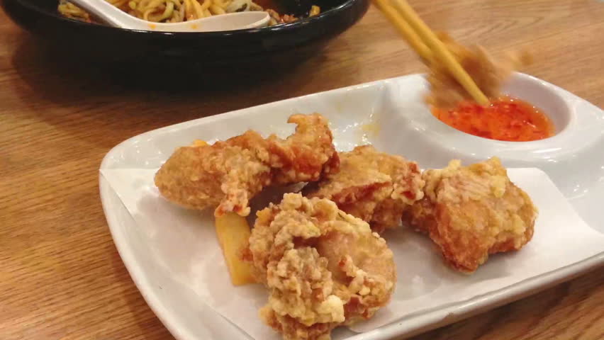 Eating fried chicken dip in sweet and spicy sauce