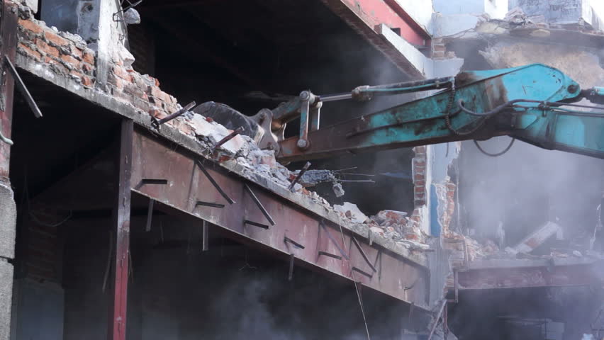 Close up shot of a condemned building being demolished with an excavator.