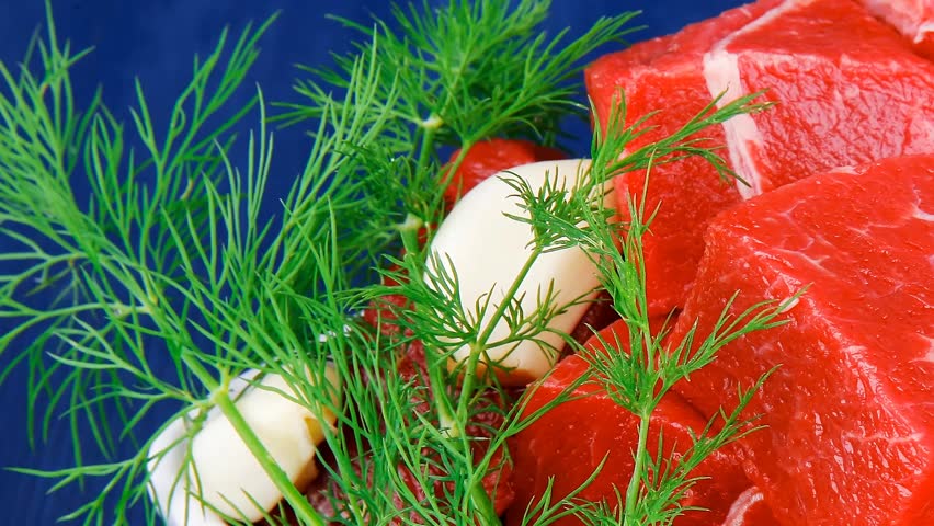 uncooked fresh beef meat chunks on white bowls with green hot peppers and vegetables serving over blue wooden table hidef intro slow motion
