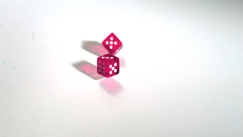 Pink dice rolling across white surface in slow motion