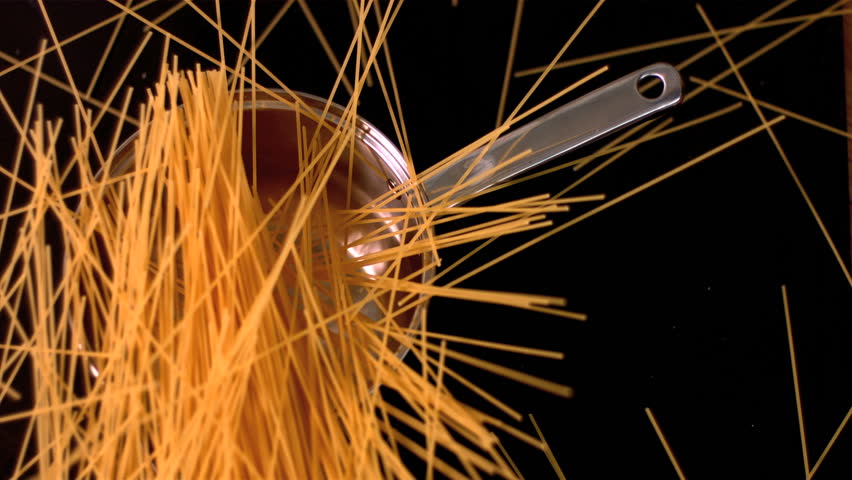 Spaghetti falling in a pot on black background in slow motion