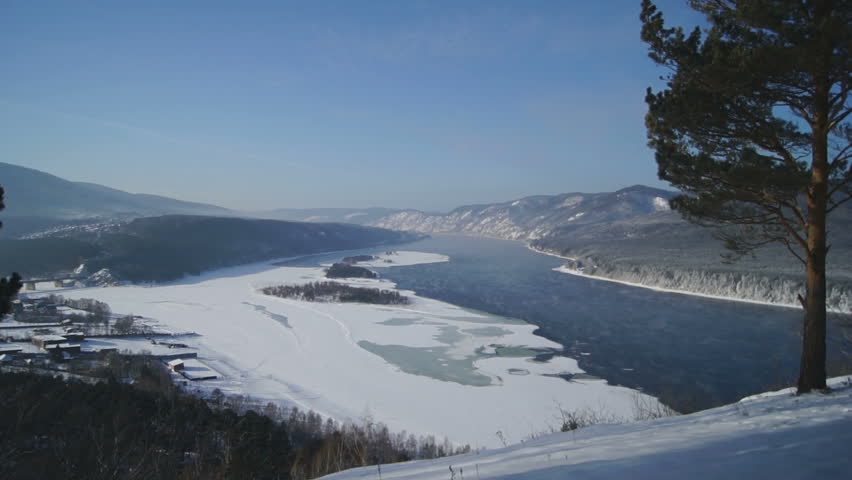 River Yenisei Winter Landscape With Pine Tree. View of the Yenisei River from a high hill on the shore. Beautiful natural scenery Siberian winter, sunny day in February 4, 2013.