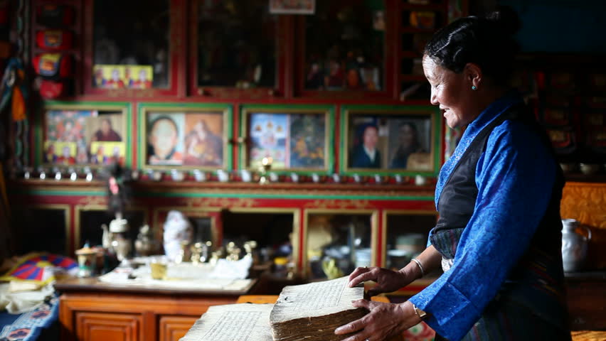 Women in traditional Tibetan dress, standing and reading old books.The dramatic light.