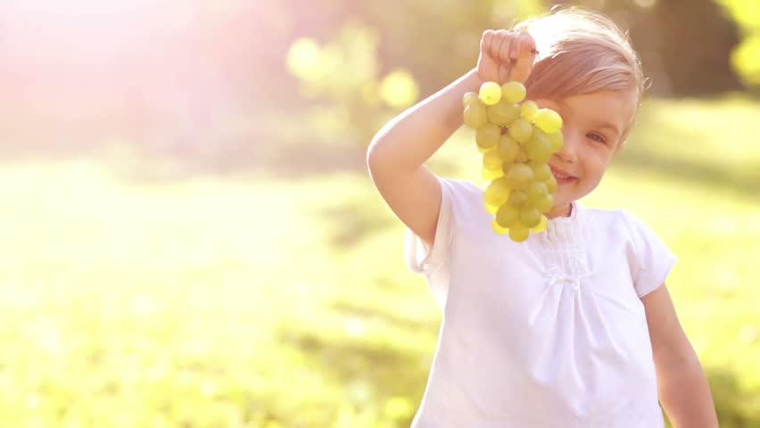 Portrait of happy girl with grapes. Thumbs up. Sign Ok.
