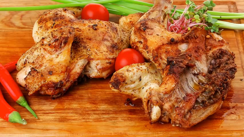 meat food : roasted chicken legs garnished with green sprouts and peppers on wooden plate hidef slow motion intro