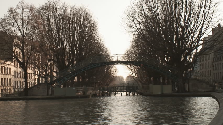 Bridge over the Saint Martin canal in Paris during winter. Pedestrian crossing and seagulls flying by.