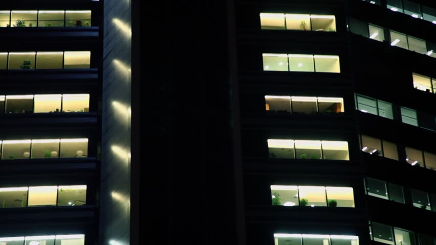Man lifts in elevator with colorful illumination by wall of office building at night