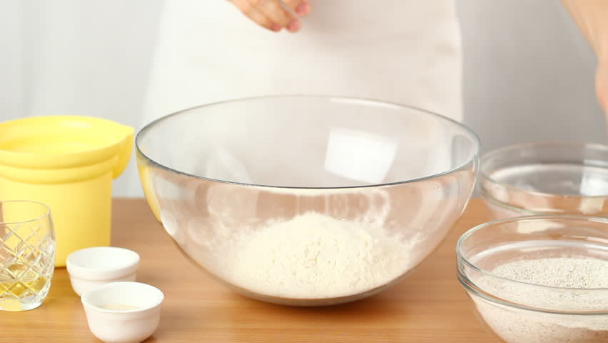 Making Bread. Series. 1/19. Baker pouring wheat and graham flour into glass bowl.