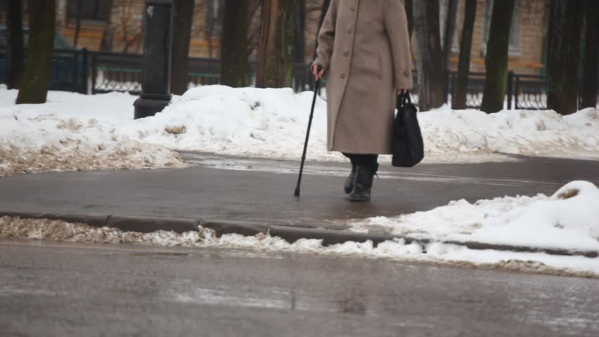 senior woman with walking-stick on winter street 