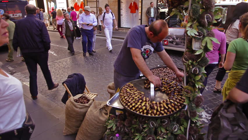 ROME - CIRCA MAY 2012: A woman notices the camera, then joins the other pedestrians walking around a man's stand on the street 