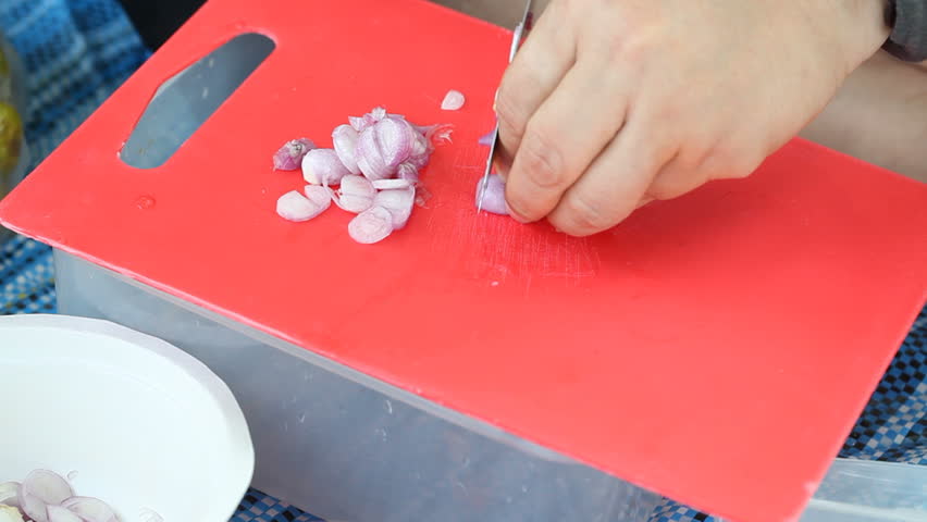 A chopped shallot on a plastic chopping board with a knife