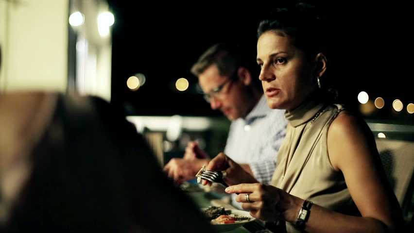 Group of friends celebrating dinner on the terrace at night, steadycam shot

