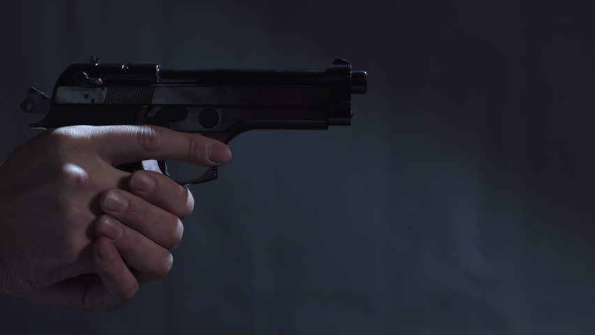 Close profile of man holding a 9 mm handgun takes three shots