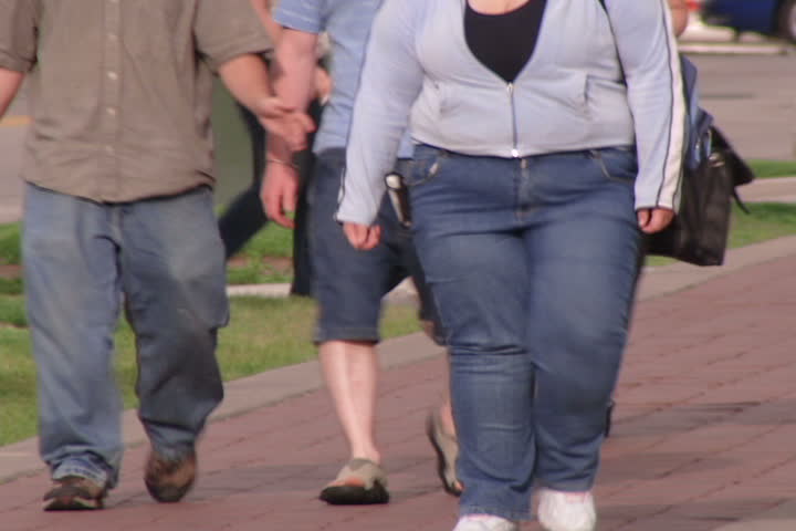 Obese people walking down urban street.