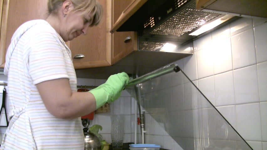 woman in gloves cleans a gas stove. 