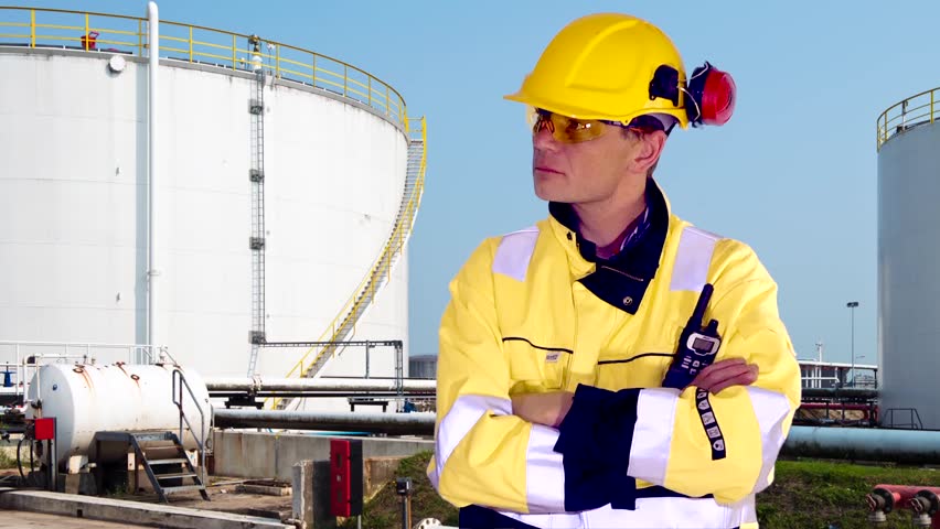 Person standing confident in front of industrial background, nodding and looking approving at camera