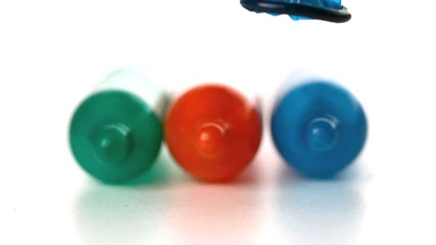 Colourful condoms falling in front of blown up condoms in slow motion
