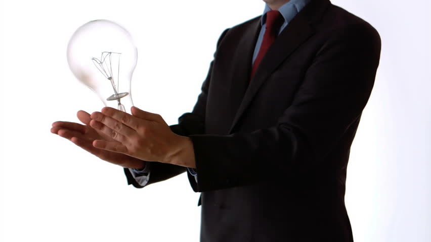 Man tossing an oversize light bulb on white background in slow motion