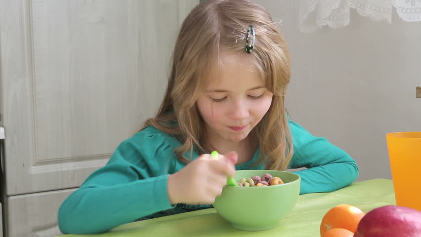 young girl eating cornflakes from the bowl