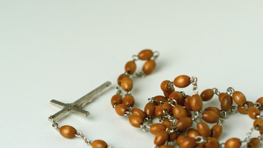 Rosary beads falling on white surface in slow motion