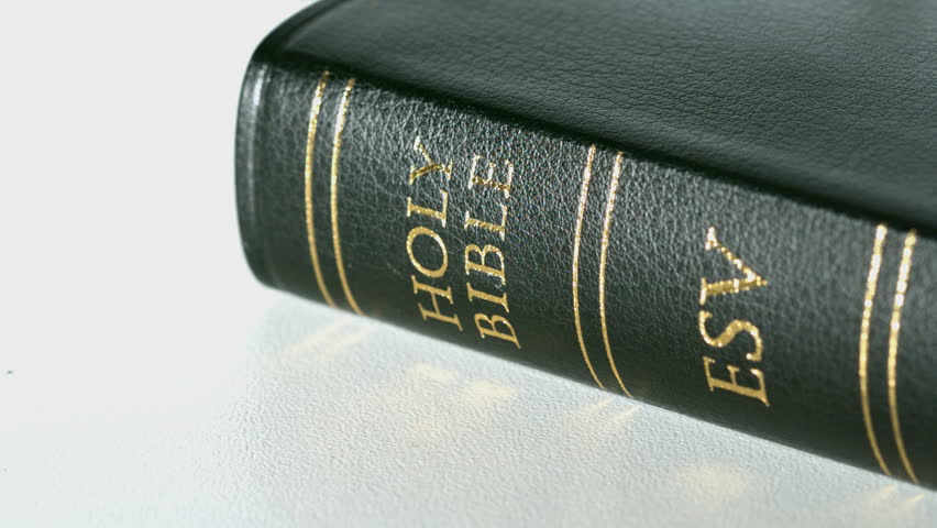Rosary beads falling onto bible in slow motion
