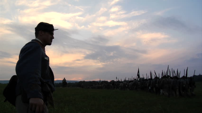 CHICKAMAUGA, GEORGIA - OCTOBER 2008 - large-scale, epic Civil War anniversary reenactment -- in the middle of battle.  Confederate Army marches across field, down hill on dirt road in column as sun sets. 