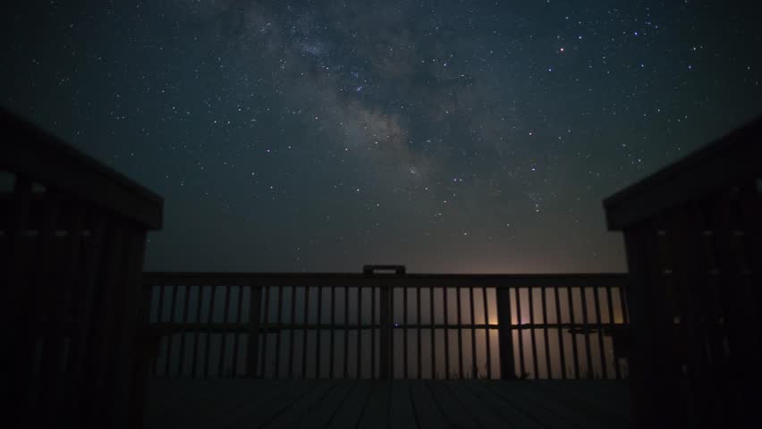 Milky Way + stars motion time-lapse with deck, car headlights, water