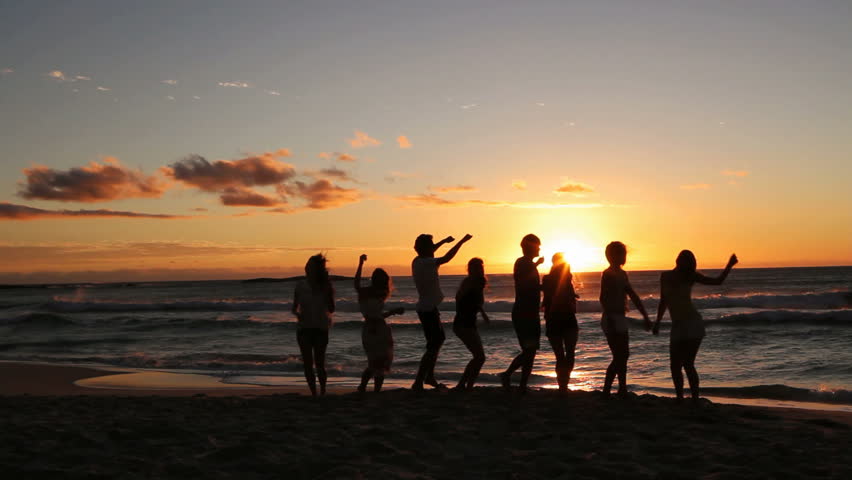 Group Of Young Hipster People dancing At Beach Party on sunset.