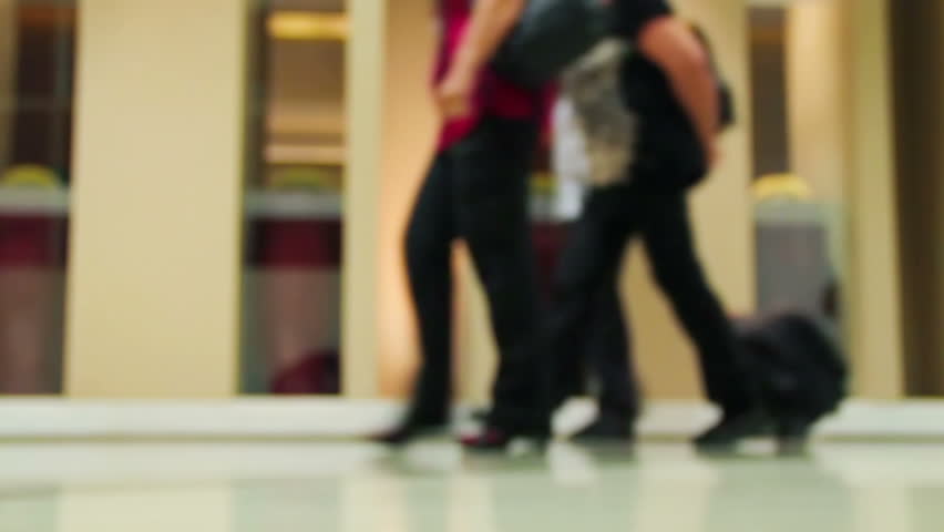 Crowd of people walking with luggage in the international airport, de-focused scene