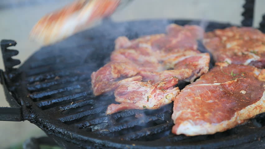 Chef cooking pork steaks on barbecue grill