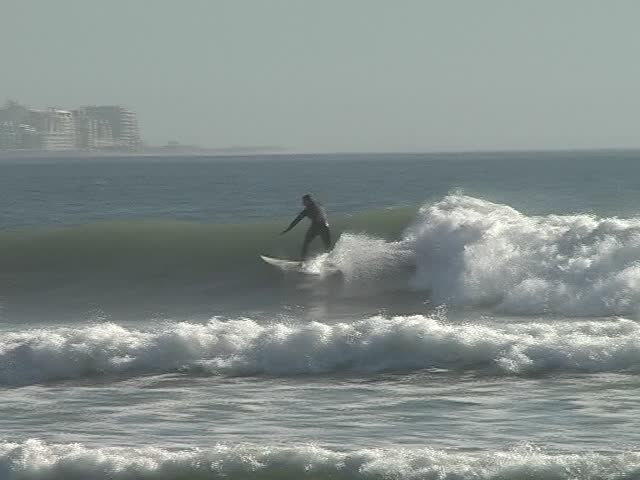 Young man surfing with his surfboard in the waves Ã¢â¬â Cape Town in background