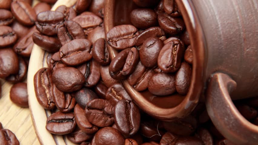 Textured background of dark arabica coffee beans/Dark brown ceramic cup full of coffee beans