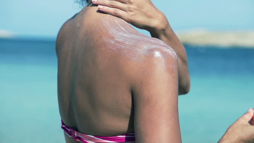 Woman applying sun lotion on her shoulders, slow motion shot at 120fps
