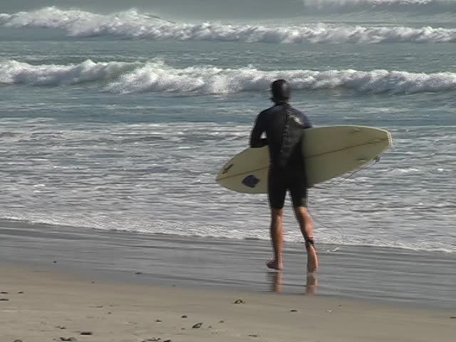 Young man running with his surfboard into the waves 
