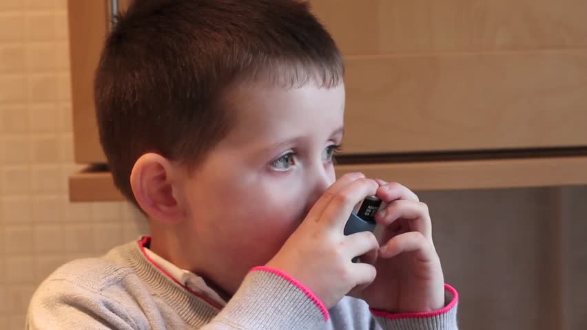 little boy inhaling his asthma pump