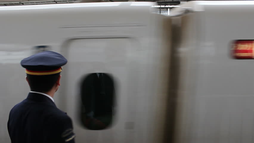 KYOTO - CIRCA MARCH 2013: A conductor gestures as a Bullet Train bound for Tokyo enters Kyoto Station in Kyoto, Japan circa March 2013.