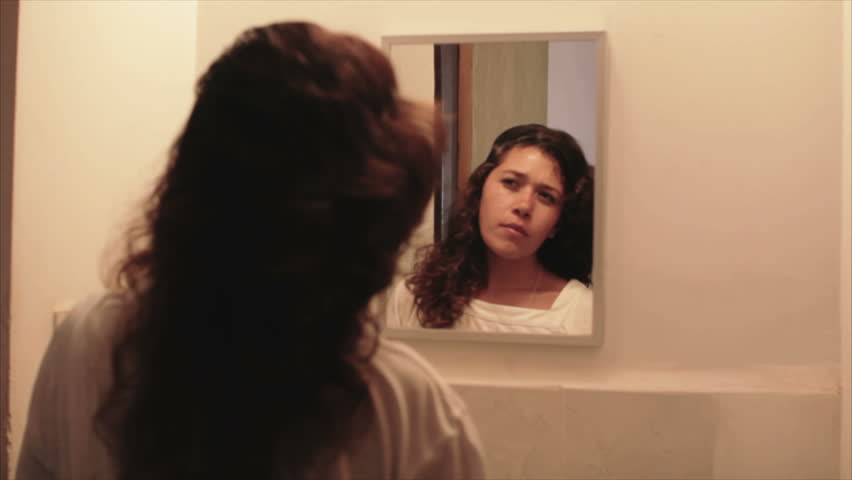 Young woman dyeing hair in front of the mirror at home