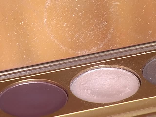 Eye shadow  and cosmetics in an open container with a mirror in the background